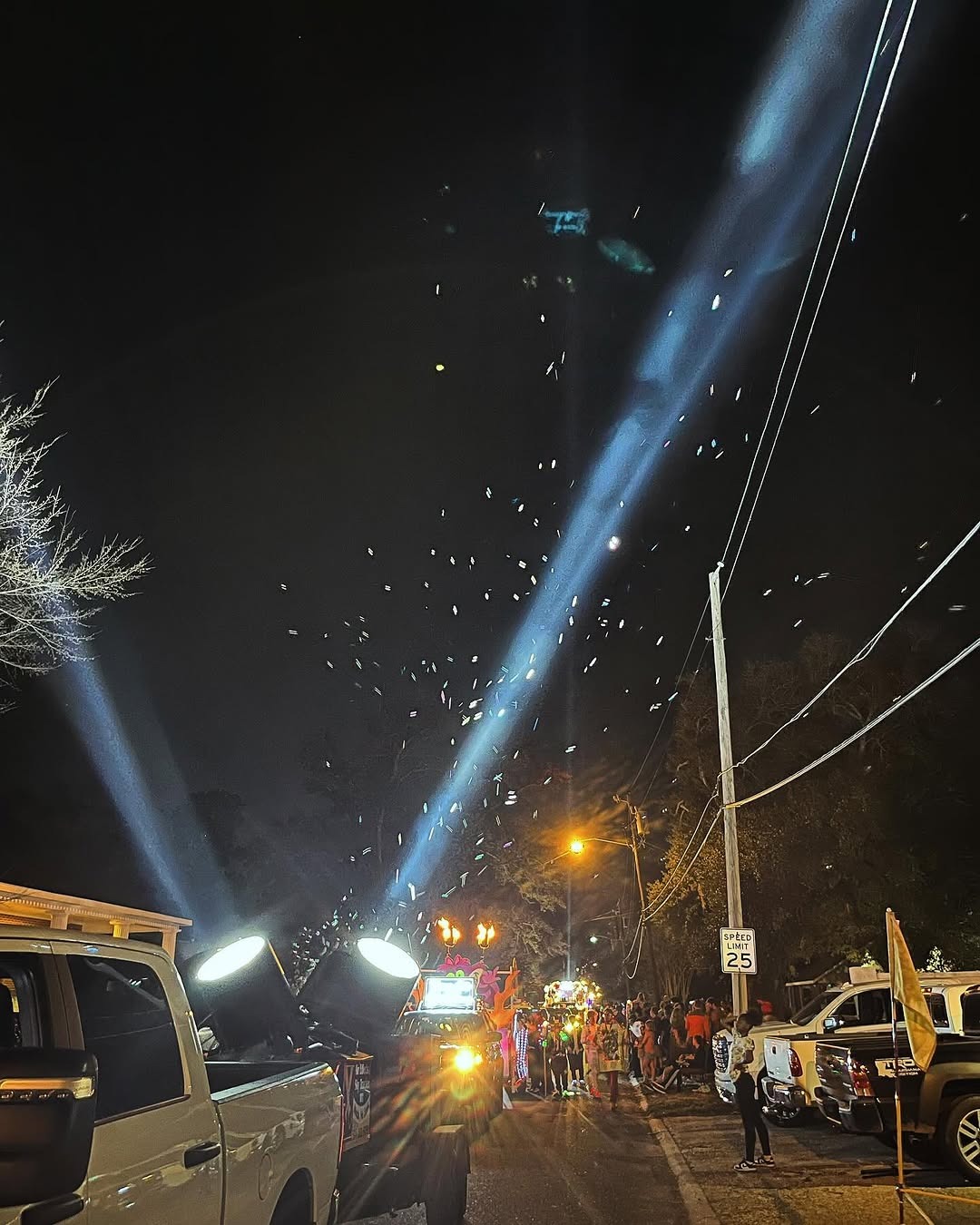 SkyTracker xenon searchlights mounted in a parade truck bed shooting beams through confetti at night